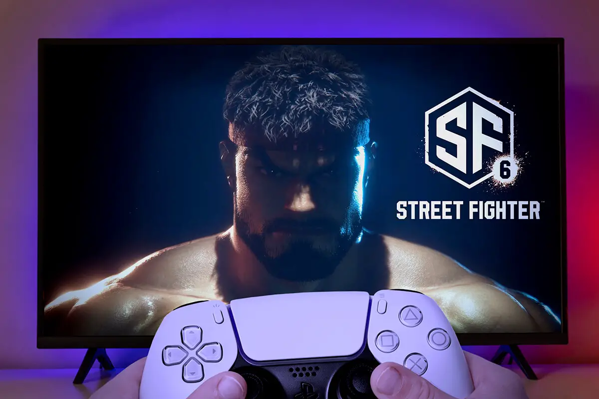Kid holding Playstation 5 controller with Street Fighter 6 logo at TV screen.