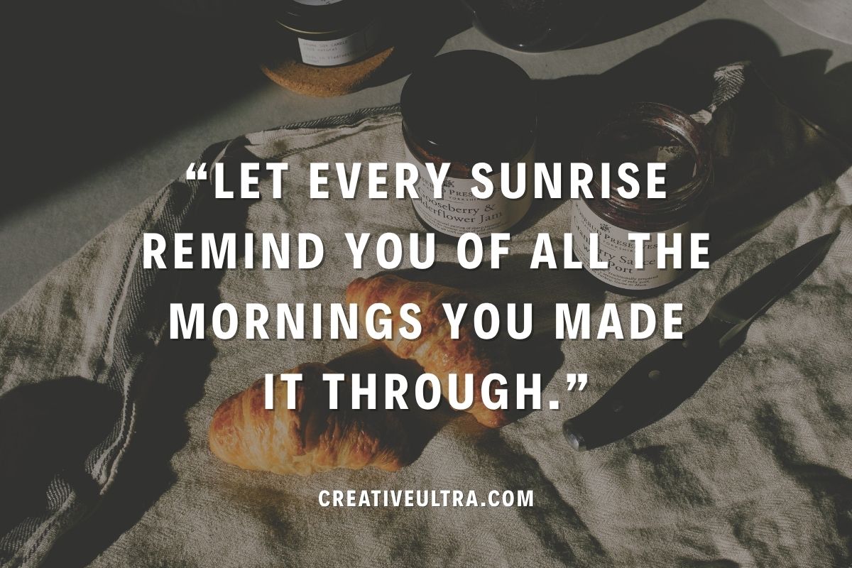 A croissant, jam jars, and a knife on a cloth with a quote overlay: "Let every sunrise remind you of all the mornings you made it through." Cozy morning vibe.